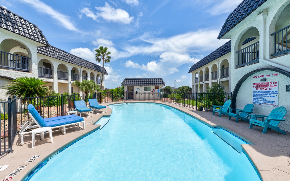 Sparkling pool awaits with comfortable loungers and colorful chairs for your perfect poolside relaxation.