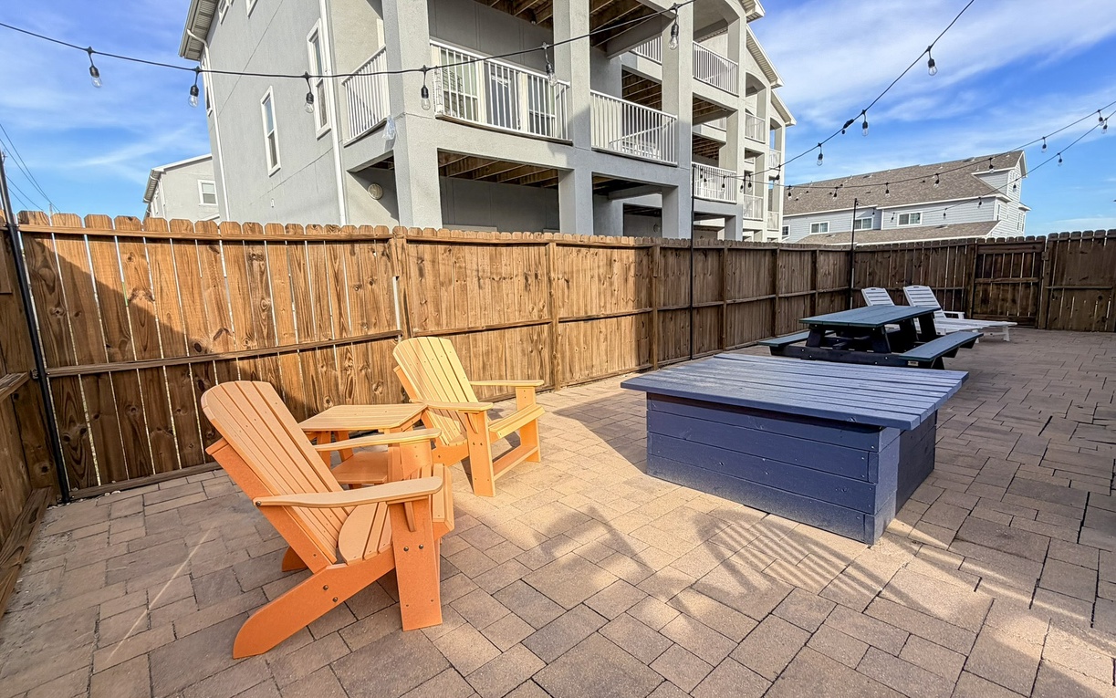 Your private outdoor oasis features colorful Adirondack chairs and dining spaces under twinkling string lights for perfect evening gatherings.