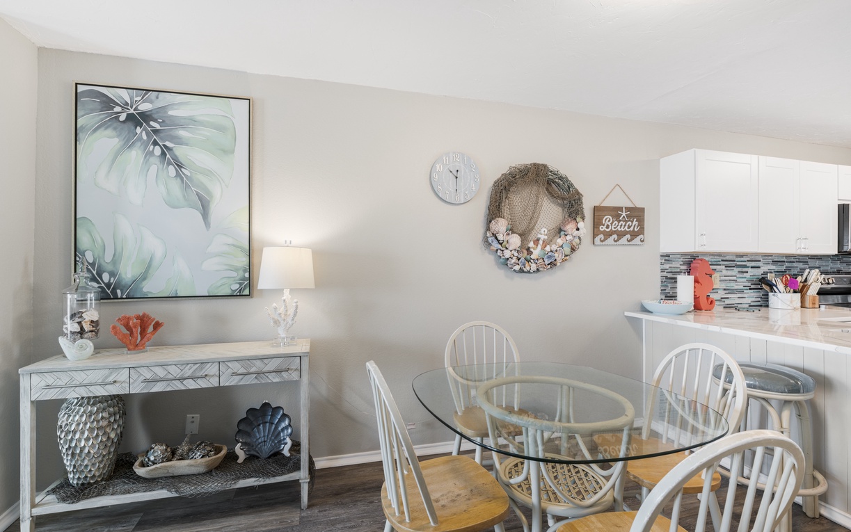 Your bright dining space features a glass table surrounded by coastal charm, where beach-inspired decor and soft lighting create perfect moments for shared meals.