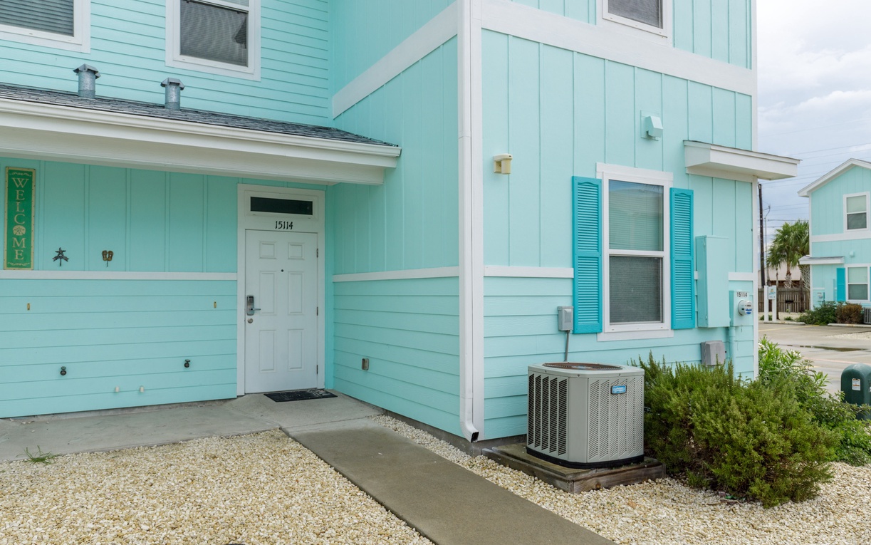 Charming turquoise beach house with welcoming entrance and tropical landscaping creates the perfect coastal getaway atmosphere.