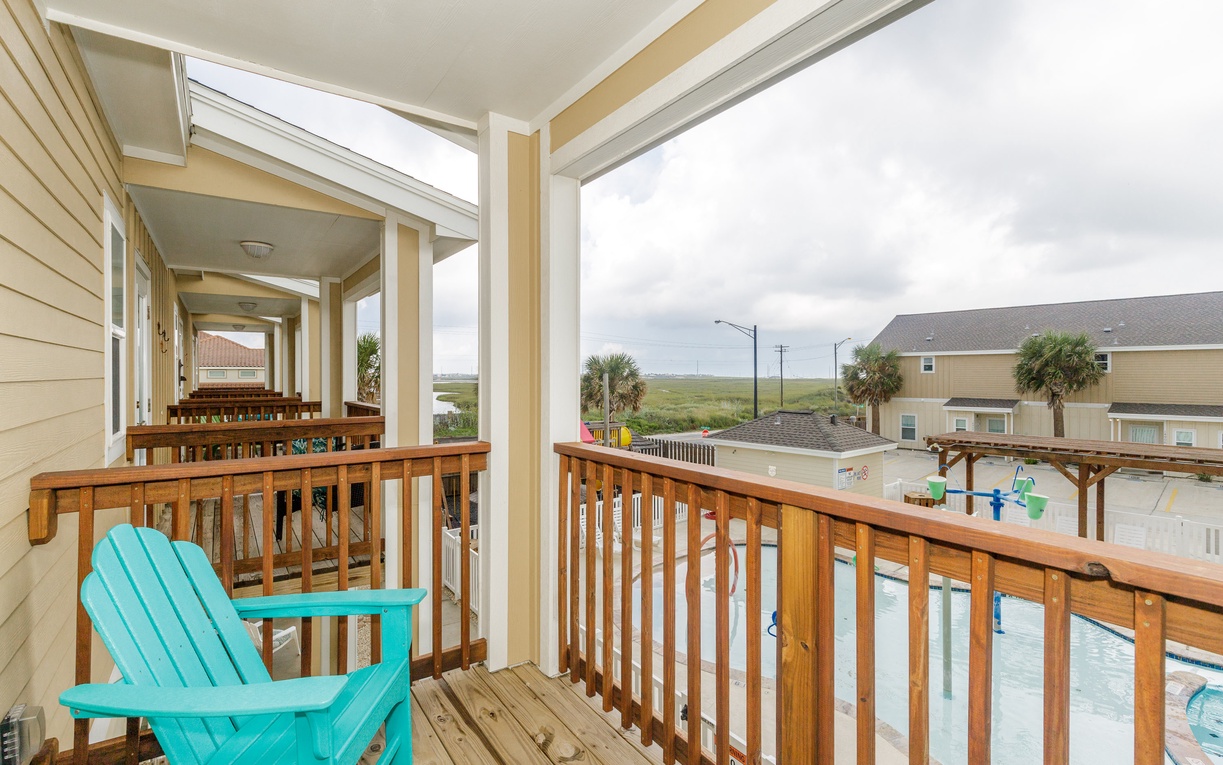Relax in your bright turquoise chair on this covered balcony, watching the pool below and distant marsh views unfold.