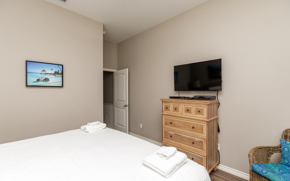 Unwind in your primary bedroom featuring a king size bed and coastal artwork to inspire sweet dreams of beach adventures.