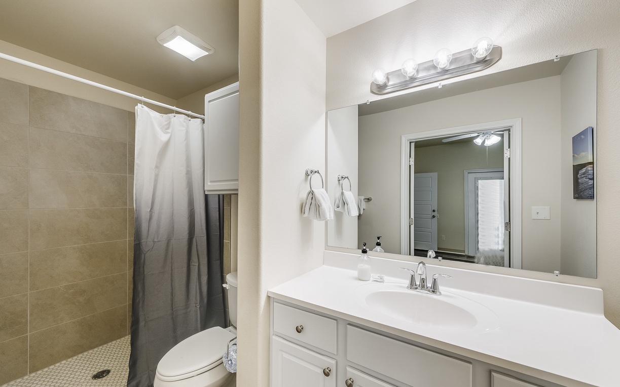 Your private bathroom features a spacious vanity with bright lighting, perfect for your morning routine, plus a refreshing tiled shower.