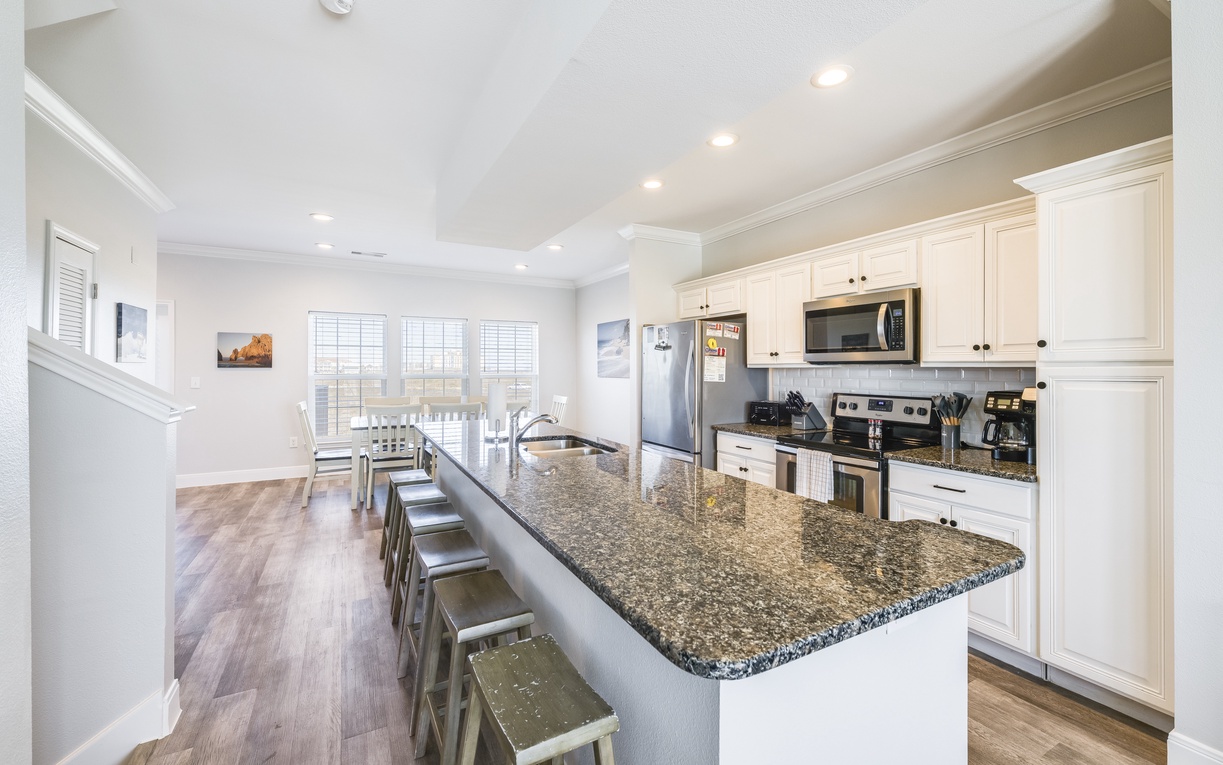 Your spacious kitchen boasts granite countertops, stainless steel appliances, and a breakfast bar perfect for morning coffee or casual dining.