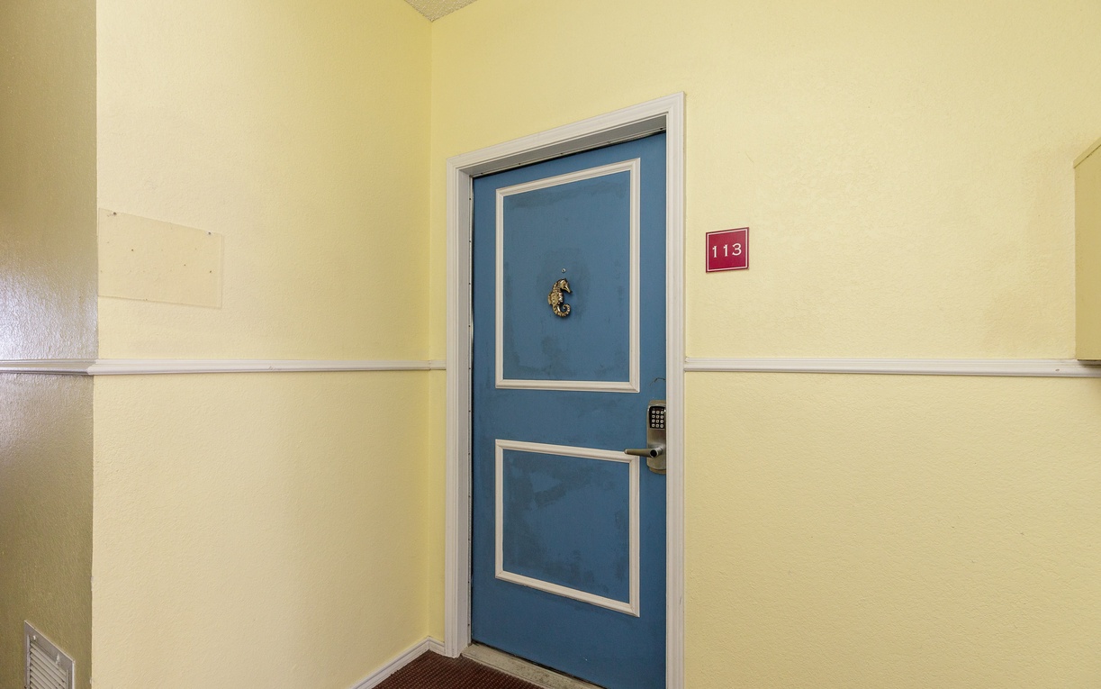 Your cheerful blue door marks the entrance to your coastal retreat, where room 113 awaits with nautical charm and home-like comfort.