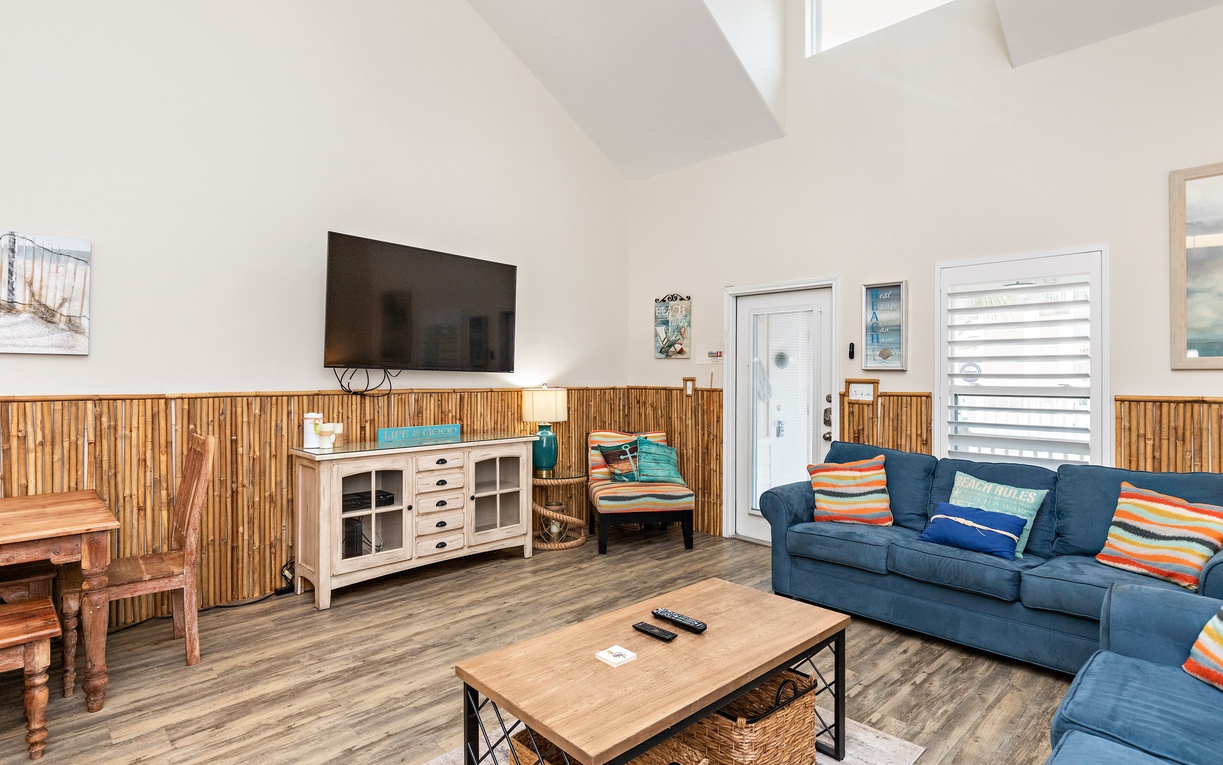Unwind in your bright living space with vaulted ceilings, bamboo accents, and cozy blue sectional perfect for movie nights.