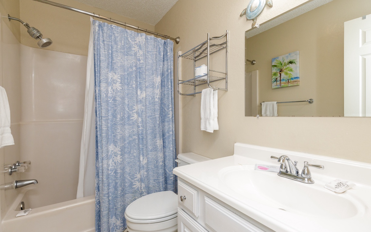 Step into your private bathroom featuring a relaxing tub-shower combo, fresh towels, and tropical-themed decor to start your day refreshed.