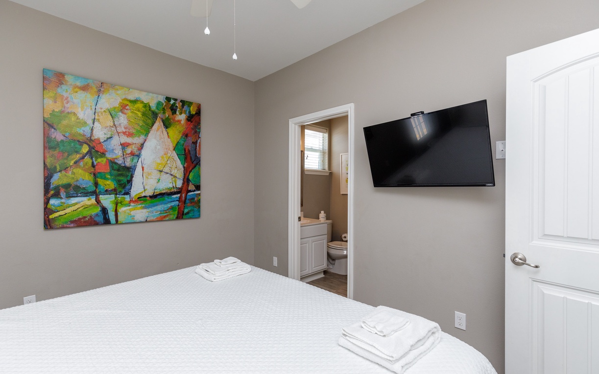 Your peaceful bedroom features vibrant artwork, a wall-mounted TV, and an ensuite bathroom for ultimate convenience.