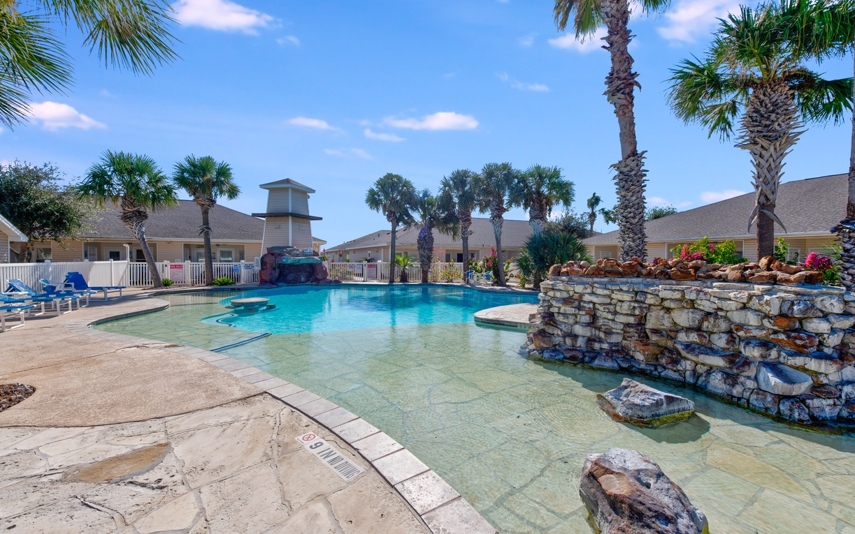 Dive into crystal-clear waters surrounded by tropical palms and stone features in this resort-style pool oasis.