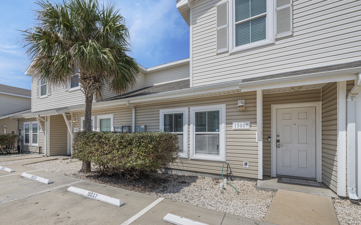 Beachside townhome with tropical palm tree and dedicated parking space, located in a peaceful coastal community.