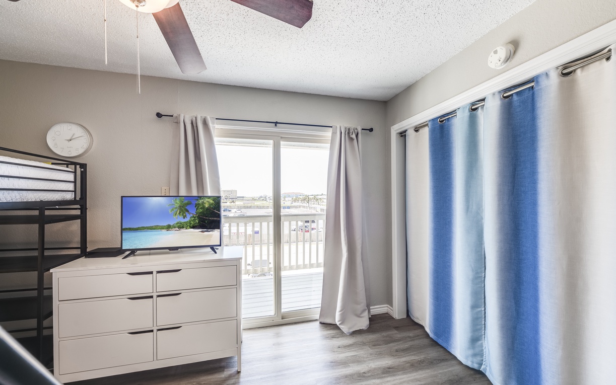 Your cozy bedroom features a bunk bed, entertainment center, and private balcony access for perfect relaxation after your adventures.