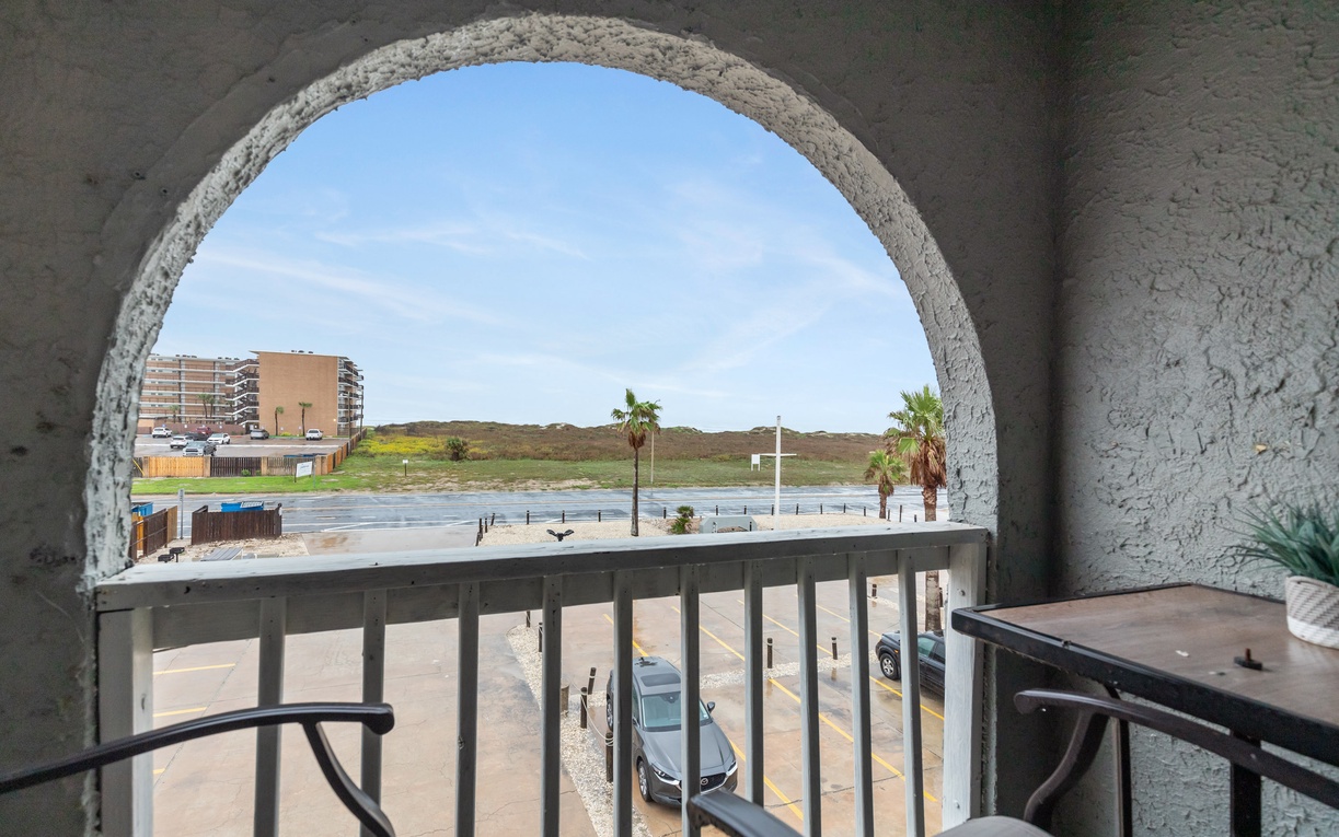 Your private balcony frames stunning views of rolling hills and distant mountains through an elegant archway.