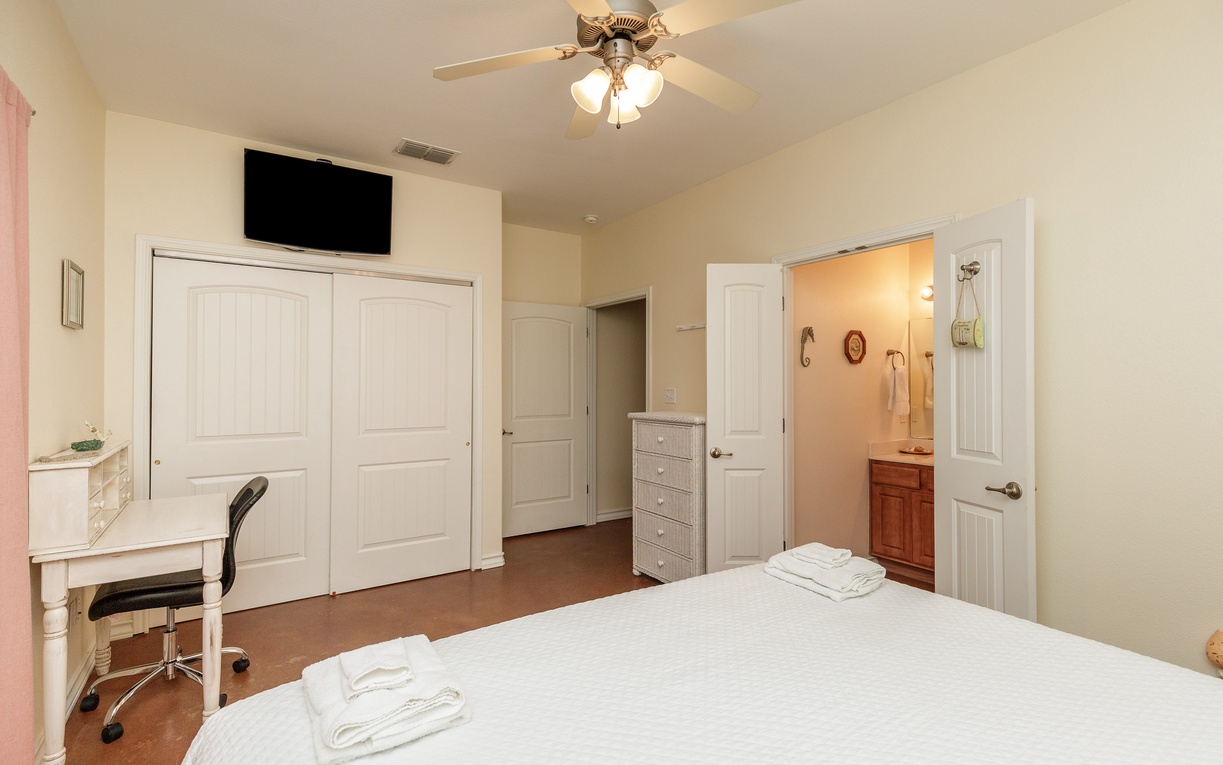 Unwind in your comfortable bedroom with ceiling fan, workspace, and private bathroom access for a restful stay.