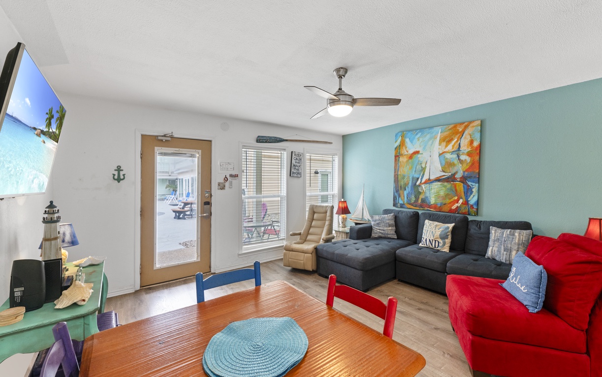 Your coastal-themed living room features comfortable seating, vibrant nautical art, and opens to outdoor dining spaces for relaxing beach getaways.