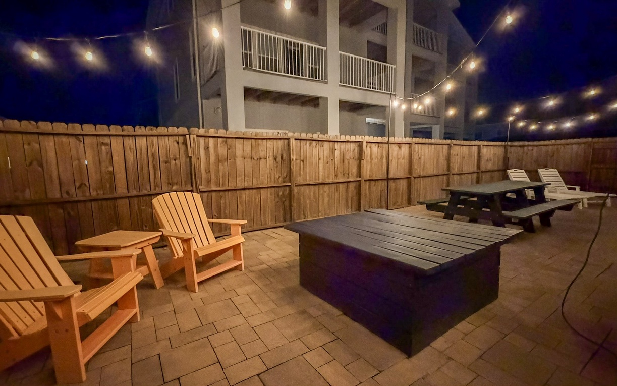 Gather around your private fire pit under twinkling string lights, where cozy Adirondack chairs and picnic tables create the perfect evening retreat.