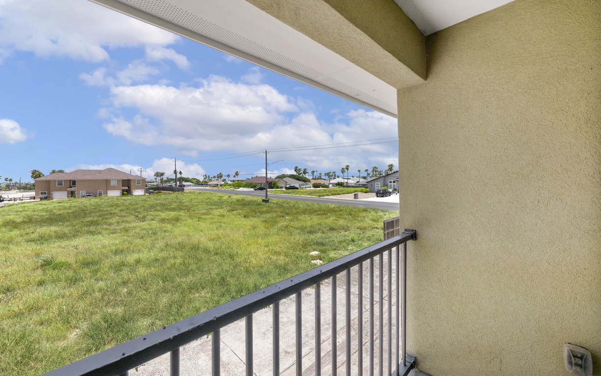 The private balcony offers views of the surrounding neighborhood, with palm trees dotting the horizon and coastal breezes welcoming you to the area.