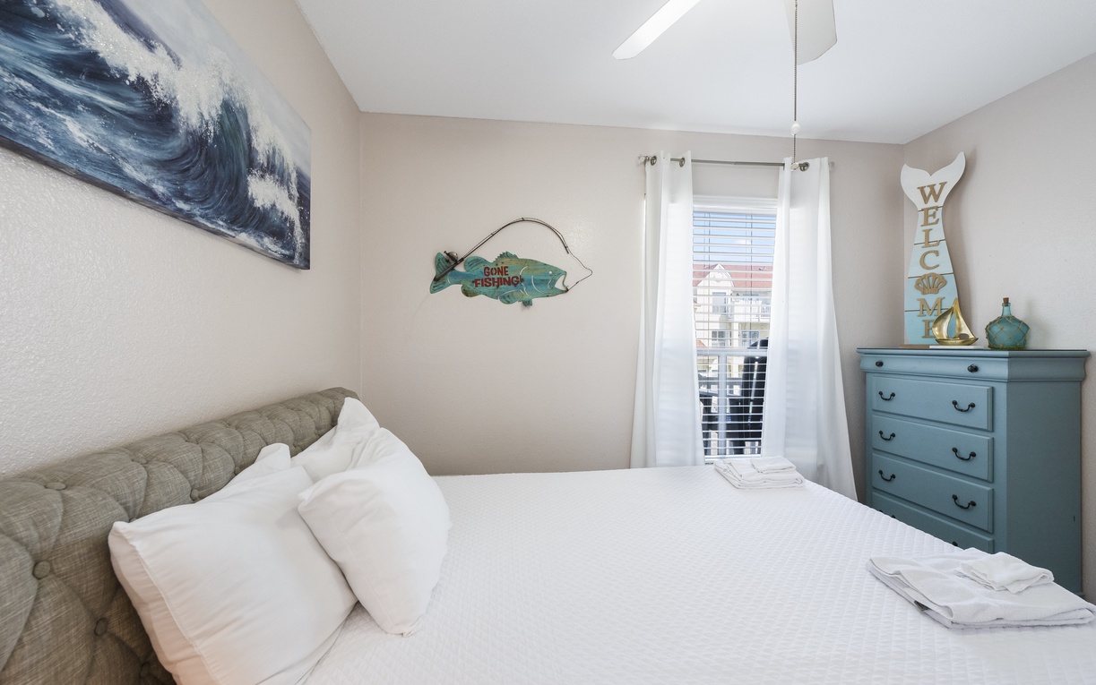 Sink into your cozy bedroom with fresh linens, charming turquoise dresser, and natural light streaming through crisp white curtains.