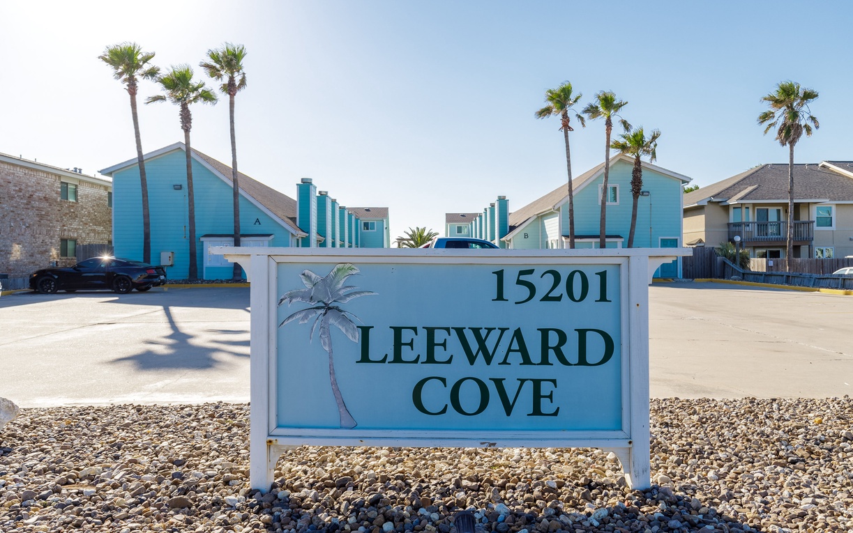 Leeward Cove property entrance with coastal-themed signage and palm-lined vacation rental buildings.