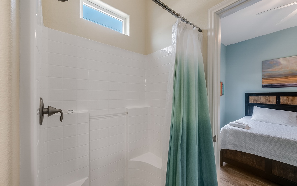 Your private shower features clean white tile and fresh linens, perfect for refreshing after exploring the area.