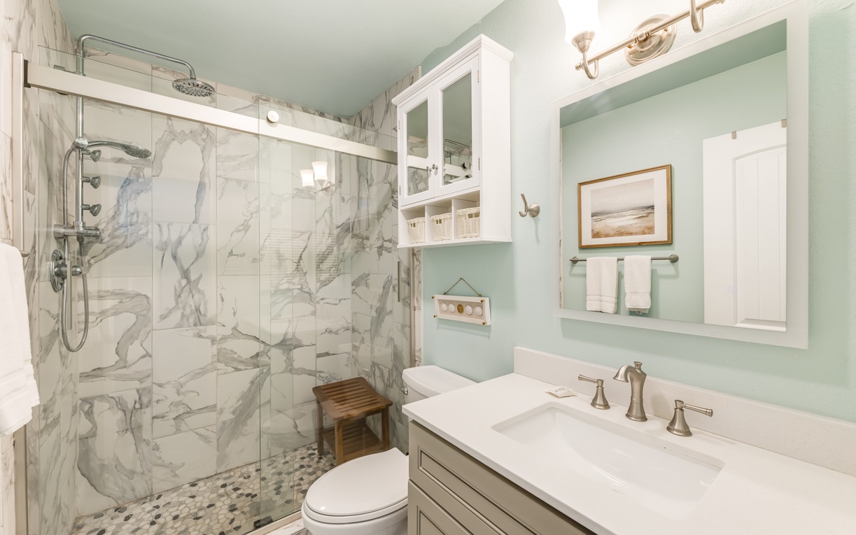 Refresh in your private bathroom with elegant marble details, a spacious walk-in shower, and coastal-inspired decor that makes every morning feel like a spa day.