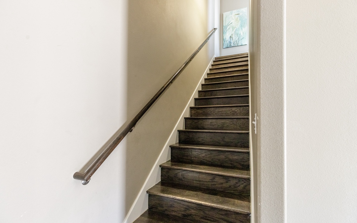 Ascend these elegant wooden stairs with sleek handrails to discover your upper-level retreat.