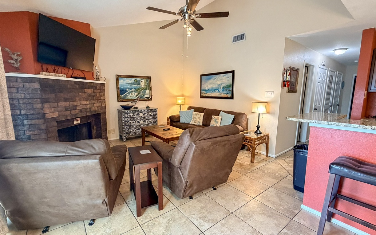 Relax in this welcoming living space with plush seating, cozy fireplace, and ceiling fan to keep you comfortable during your stay.