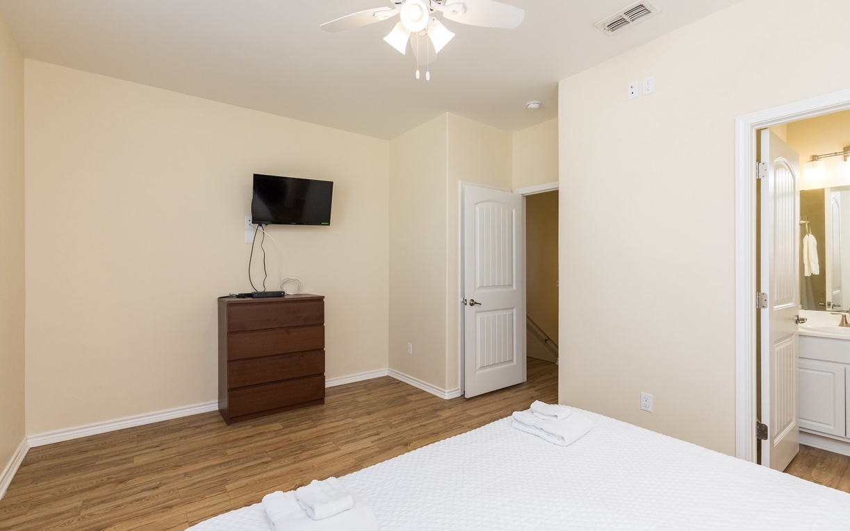 Your spacious bedroom features warm wood floors, a ceiling fan for comfort, and convenient TV for relaxation after exploring.
