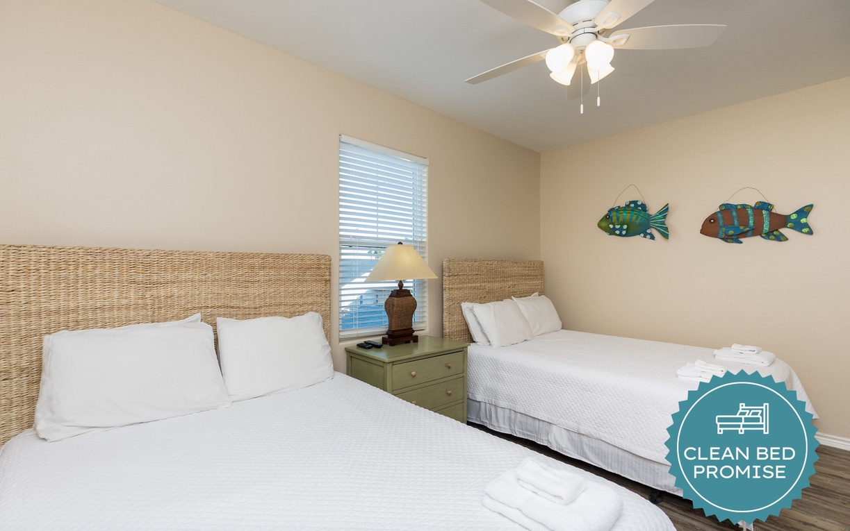 Relax in this cheerful twin bedroom featuring wicker headboards, crisp linens, and playful fish art that creates a coastal feel.