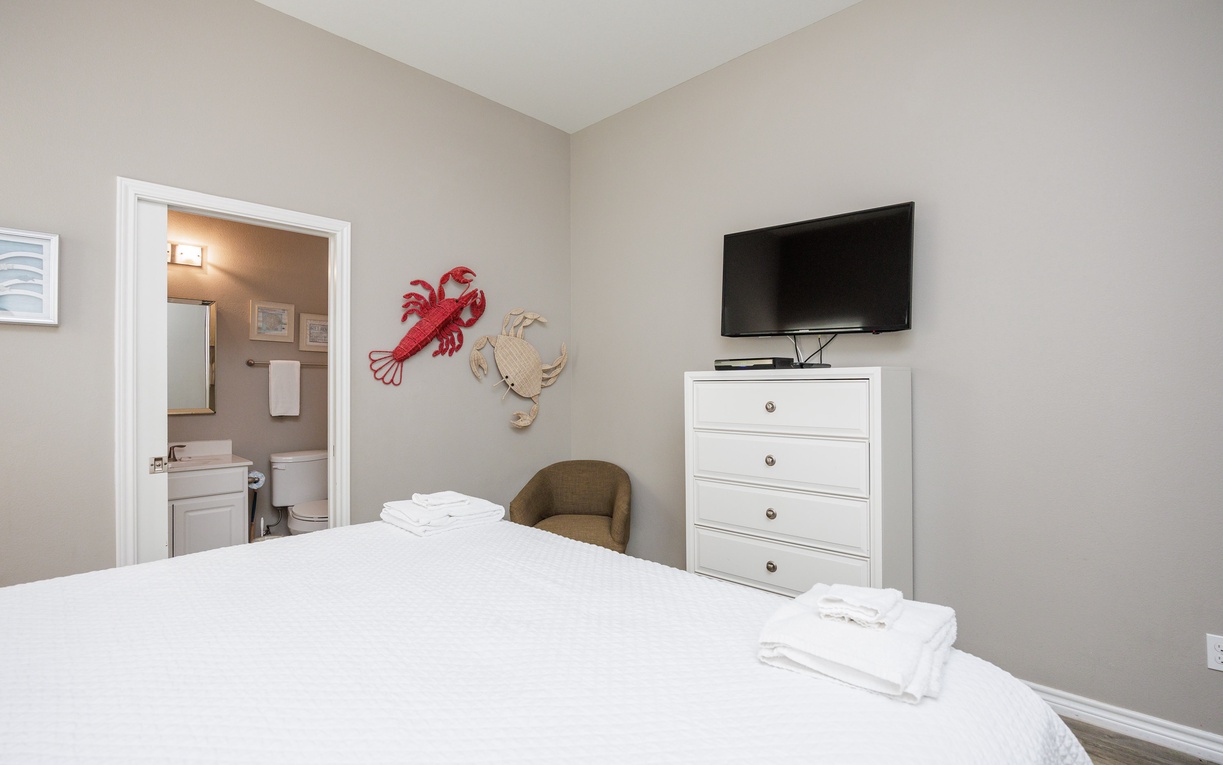 Sink into crisp white linens in your serene bedroom, complete with coastal charm and modern amenities for ultimate comfort.