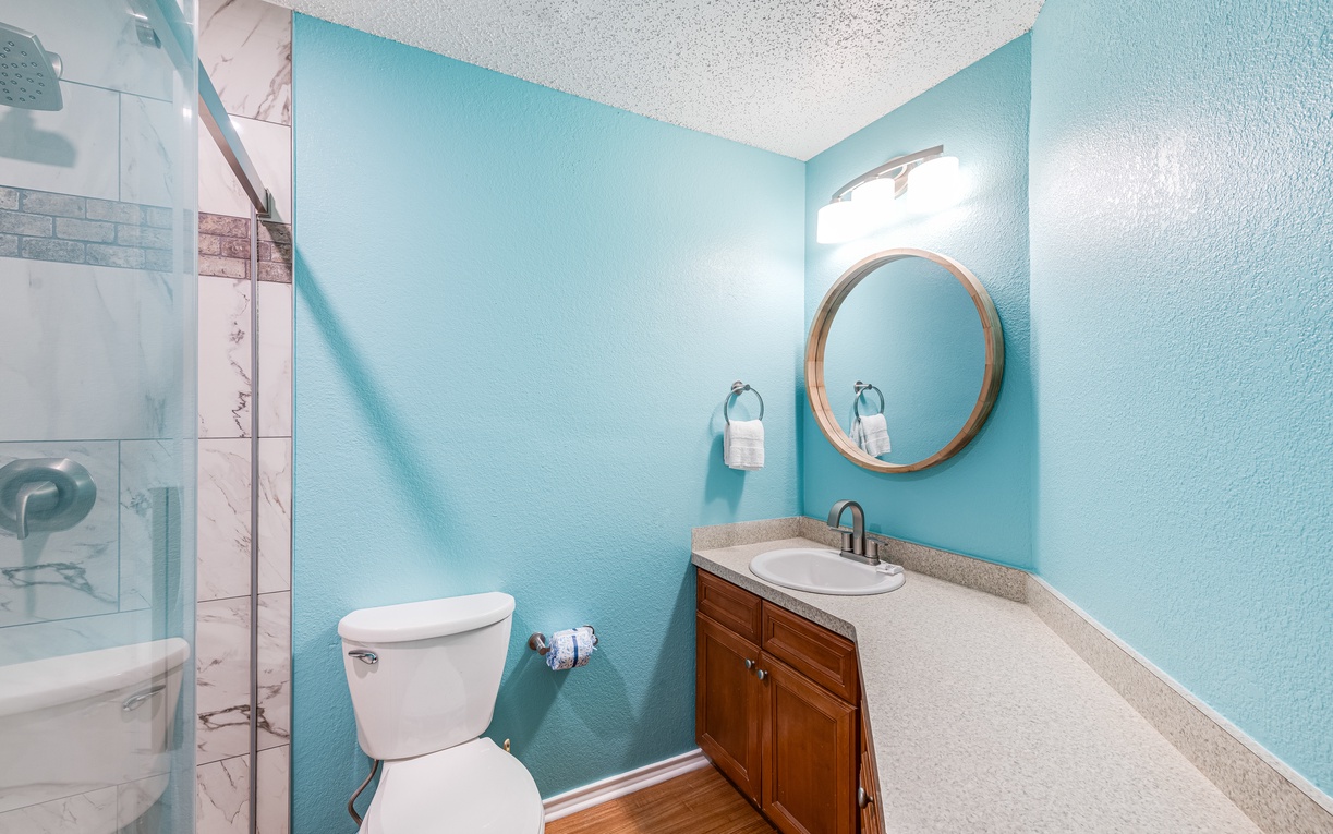 Step into your serene bathroom retreat with calming aqua walls, elegant marble shower, and warm wood accents that create a spa-like escape.