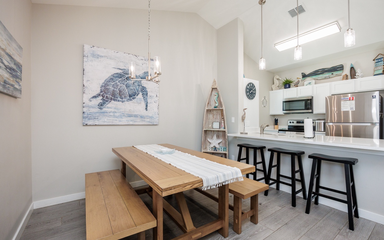Your coastal kitchen flows seamlessly into the dining space, where ocean-inspired art sets the perfect mood for memorable meals.