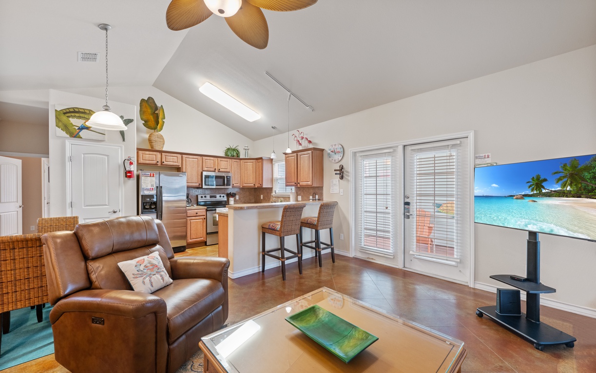 Relax in your open-plan living space with leather recliners, tropical ceiling fans, and a fully equipped kitchen—perfect for your beach getaway.