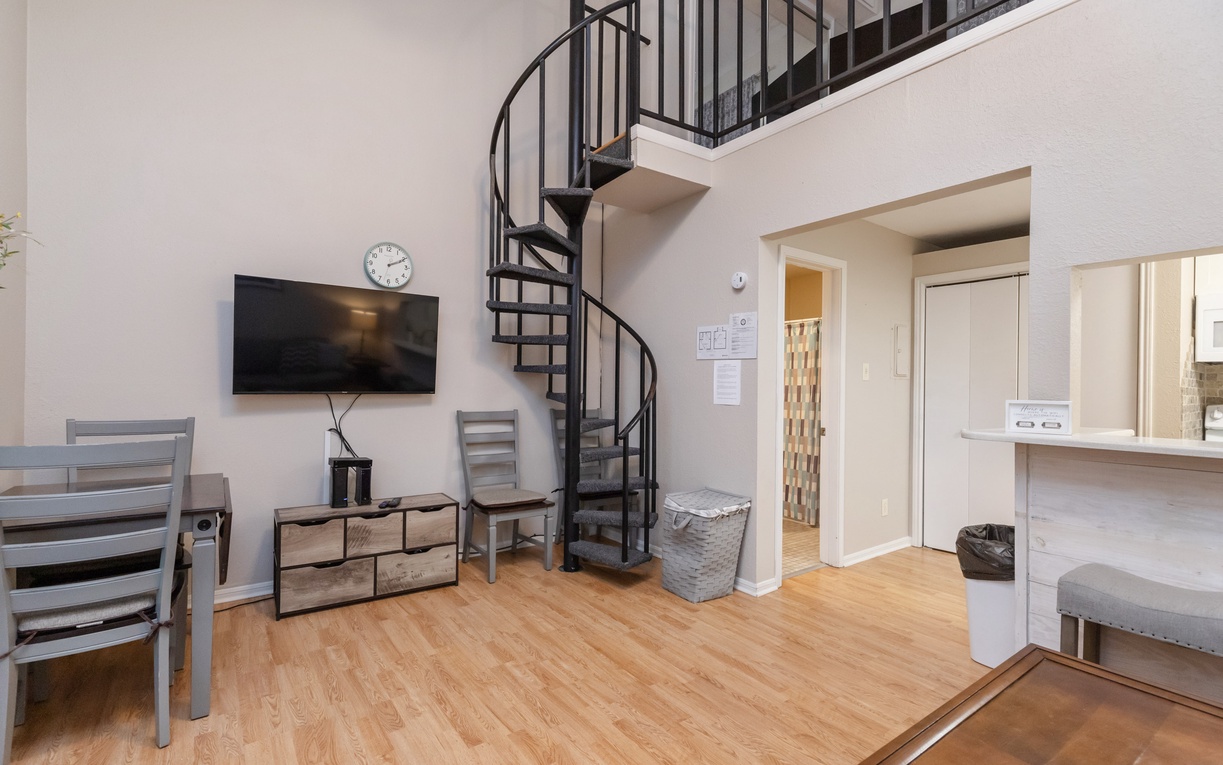Your stylish loft features a dramatic spiral staircase and open layout, with a cozy seating area and modern amenities for a comfortable stay.
