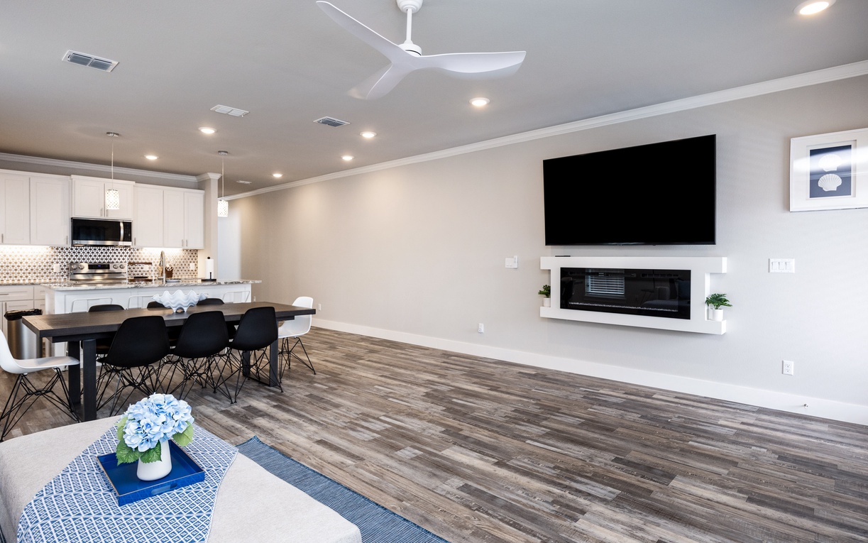 Relax in your stylish open-plan living space with modern fireplace, large TV, and sleek kitchen perfect for entertaining.