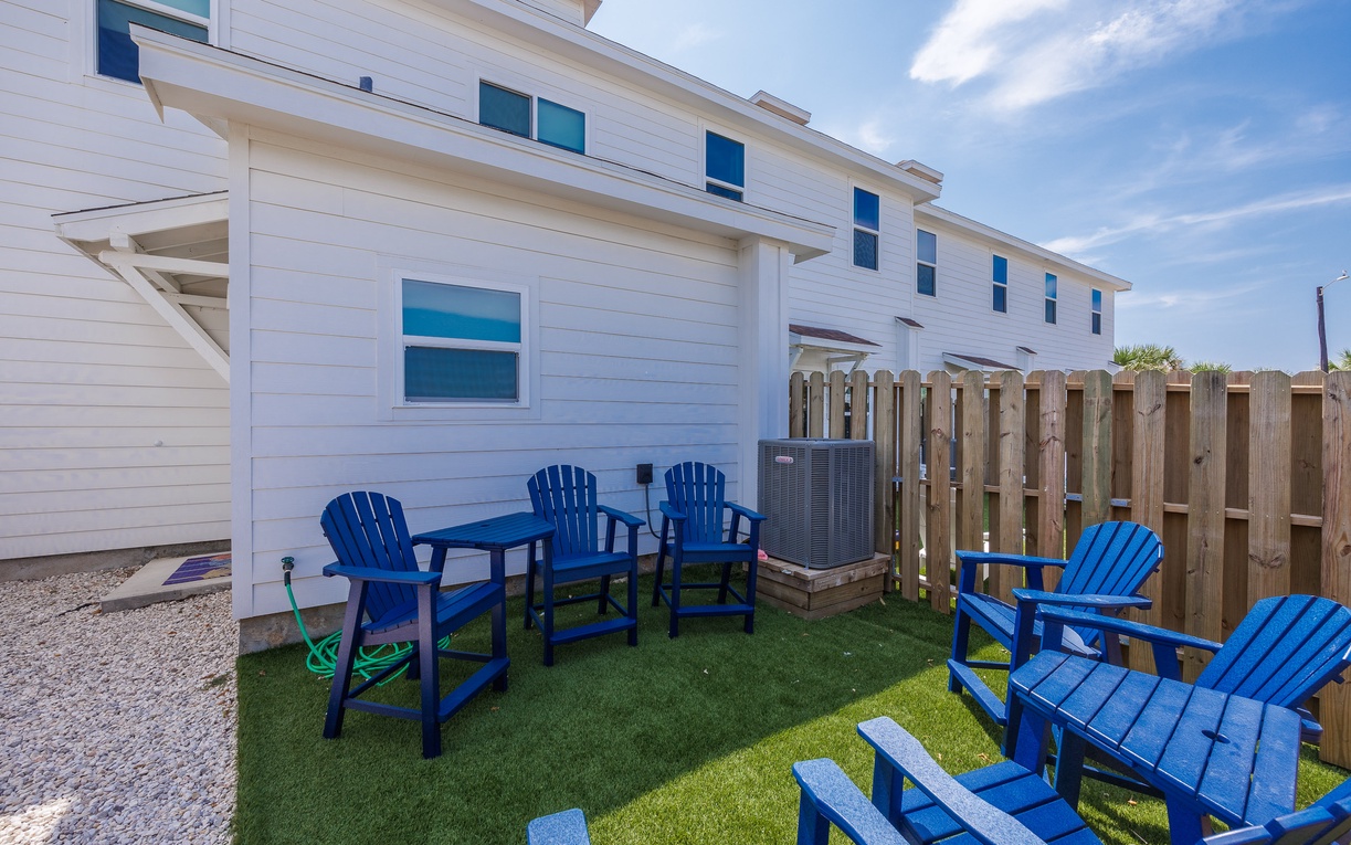 Relax in your private backyard oasis with comfortable blue Adirondack chairs perfect for morning coffee or evening conversations.