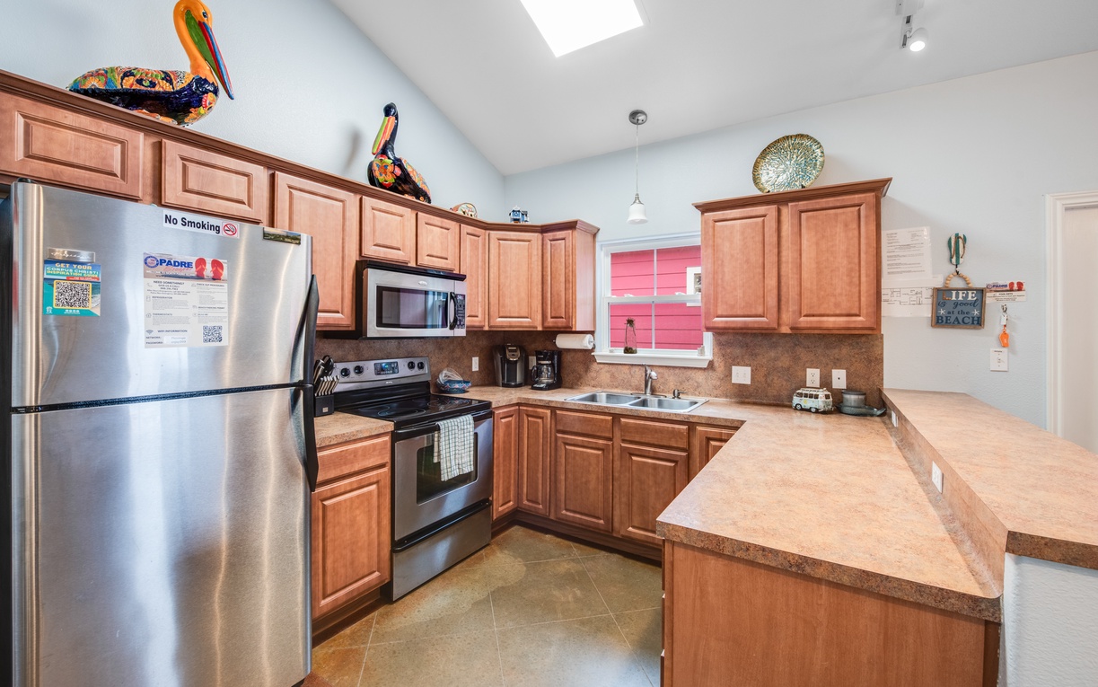 Cook your favorite meals in this fully equipped kitchen with modern appliances, ample counter space, and warm wood cabinetry.