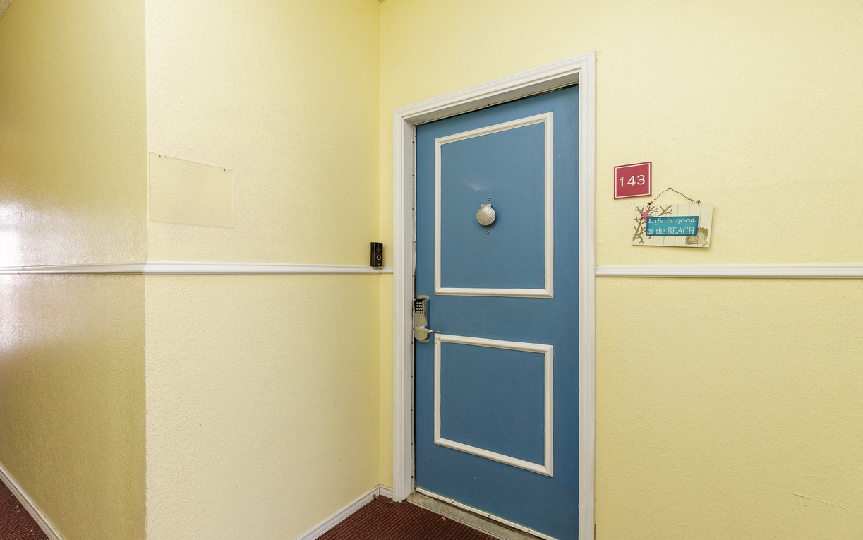 Your beach-themed room awaits behind this charming blue door in the sunny hallway.