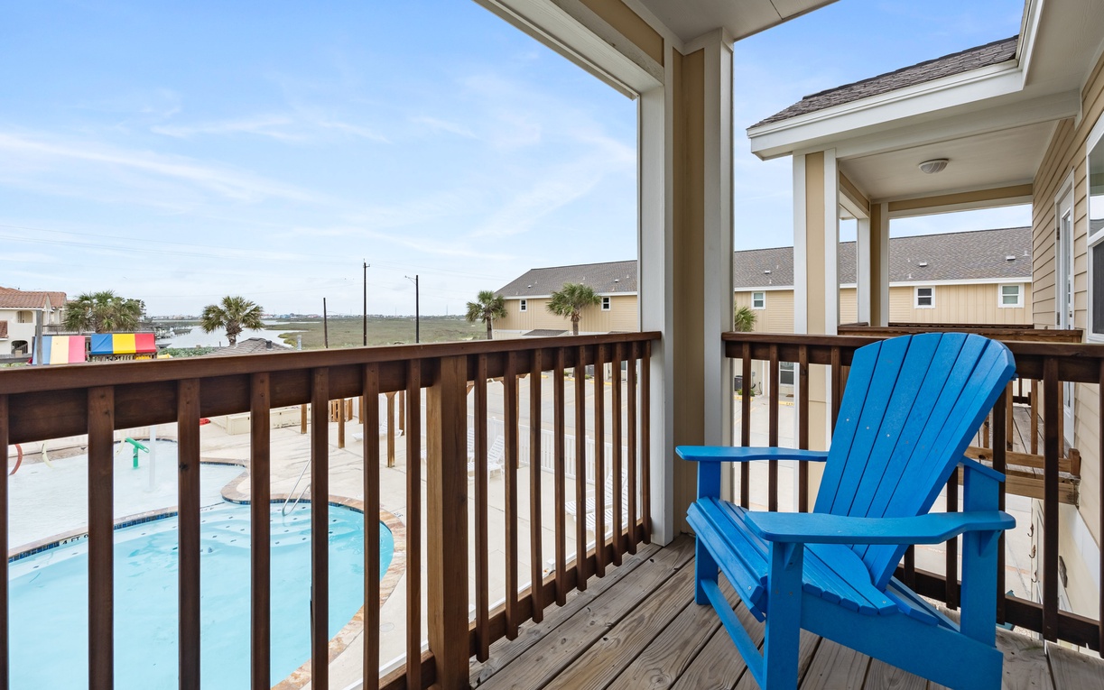 Step onto your private balcony and sink into the bright blue chair, overlooking the sparkling pool and coastal views beyond.