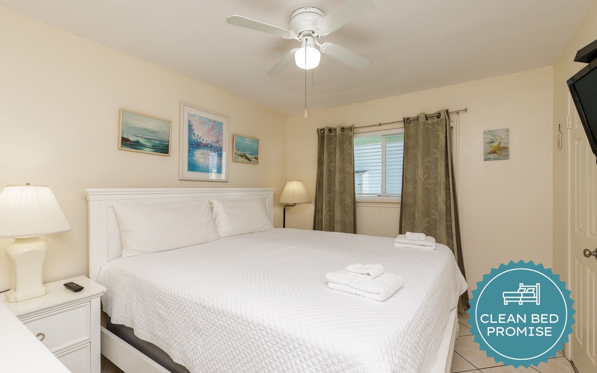 Drift off in your serene bedroom with coastal artwork and crisp white linens, where the ceiling fan keeps you cool all night.
