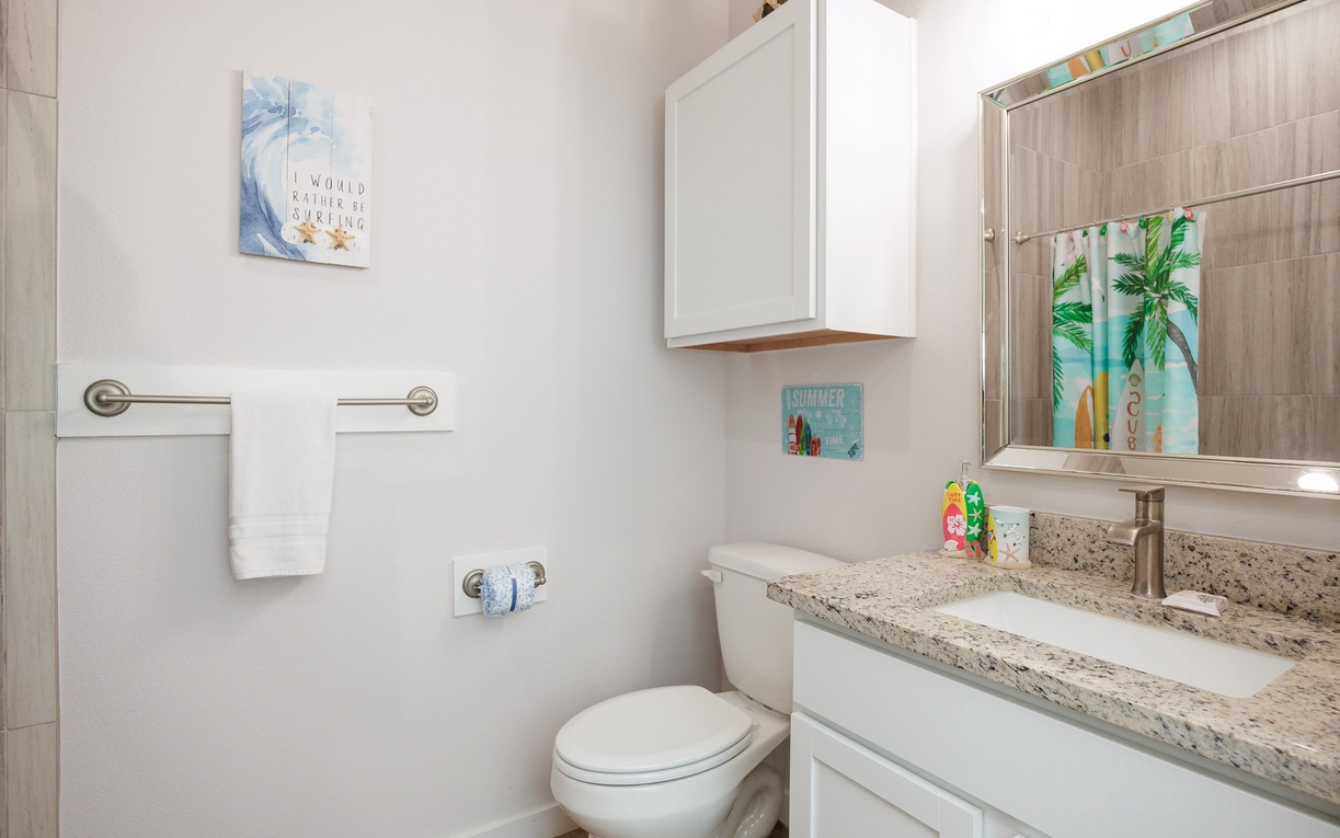 Refresh in your bright, coastal-themed bathroom featuring granite counters, ample storage, and cheerful beach artwork.