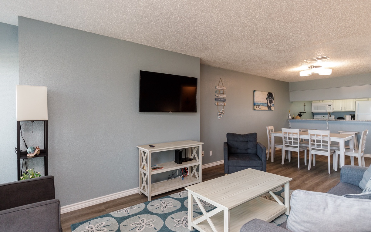 Unwind in your spacious living room featuring a large smart TV, cozy seating, and open-concept design flowing to the dining area.