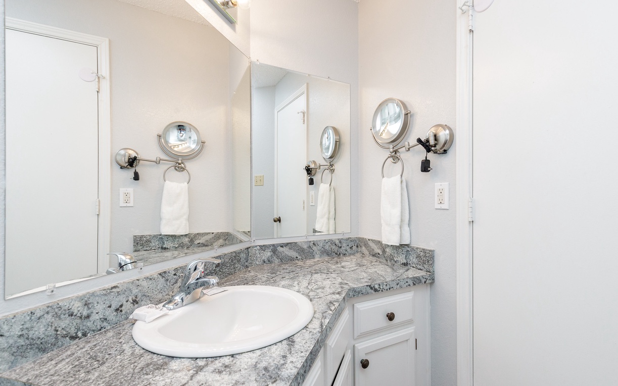 Your private bathroom features elegant granite countertops and illuminated vanity mirrors, creating the perfect space for your morning routine.