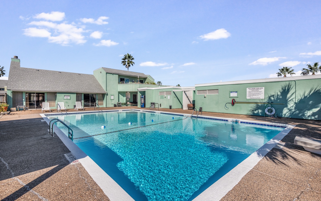 Sparkling pool with crystal-clear water awaits your refreshing swim under sunny skies and swaying palms.