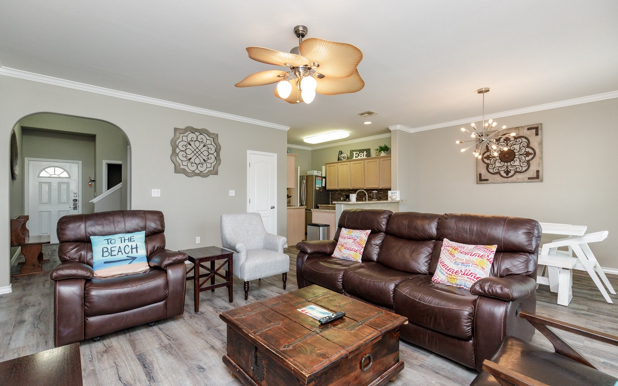 Relax in your spacious open-concept living area with plush leather seating, tropical ceiling fan, and seamless flow to the fully equipped kitchen.