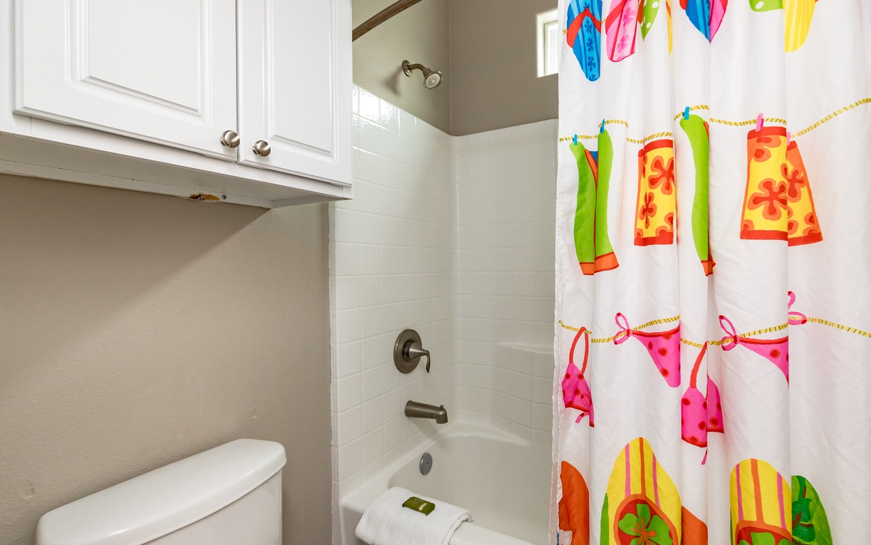 Step into your cheerful bathroom featuring a tub-shower combo and playful beachwear-themed curtain that adds tropical vibes to your daily routine.