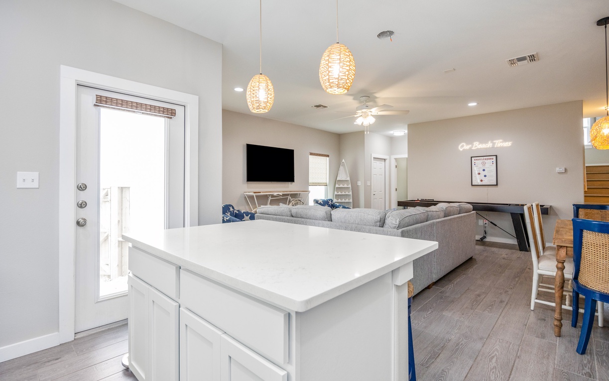Unwind in your bright, modern living space featuring stylish pendant lights and a sleek kitchen island perfect for gathering.