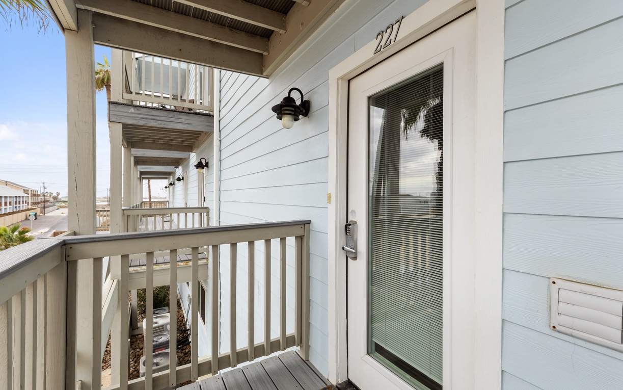 Property entrance with address number 227 featuring a covered walkway and access to beach community.