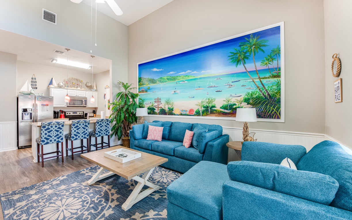 Sink into plush turquoise seating while gazing at tropical paradise artwork. Your open living space flows seamlessly to the kitchen, perfect for gathering.