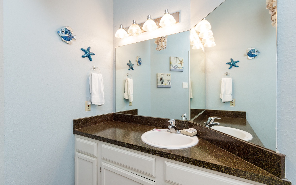 Freshen up in your charming coastal bathroom with ocean-themed décor and bright vanity lighting.
