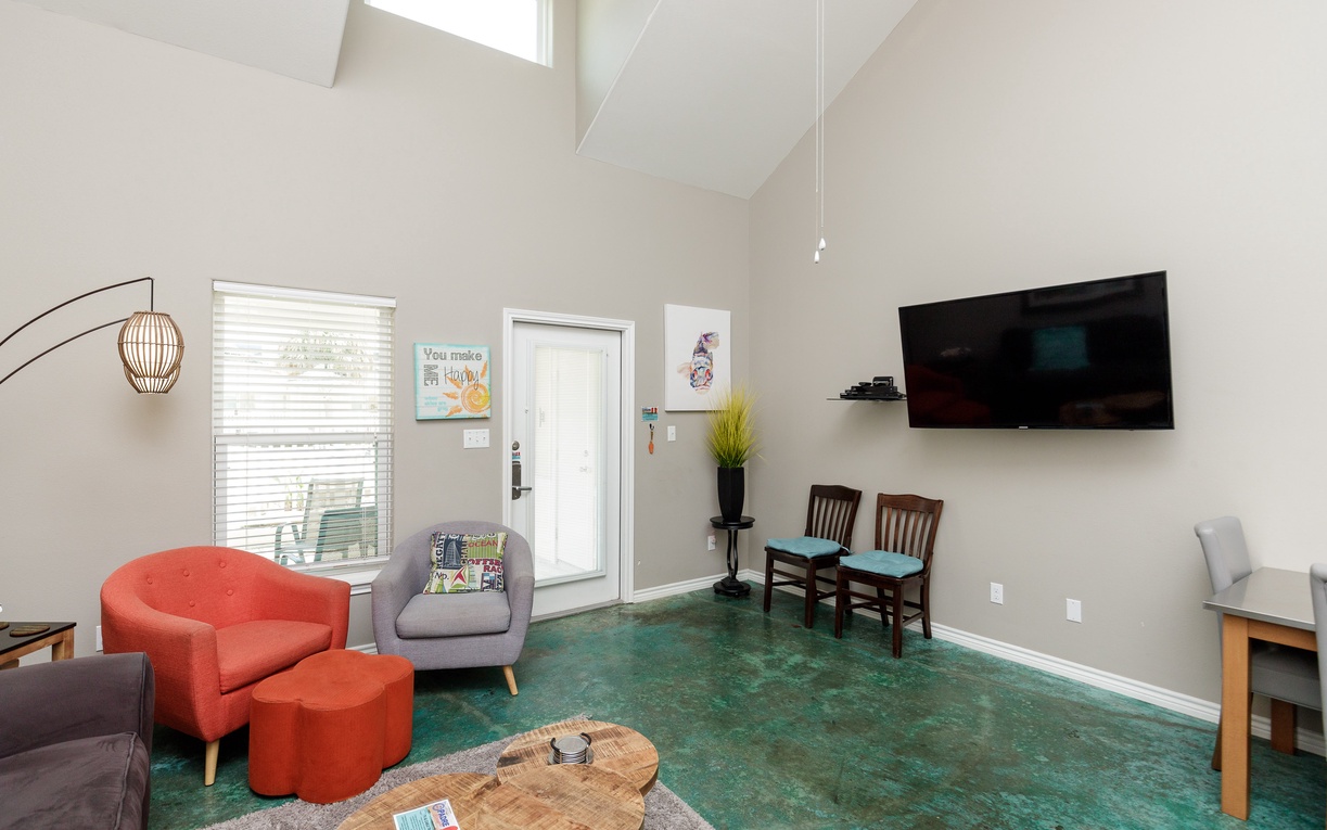 Your bright living space features soaring ceilings, vibrant turquoise carpet, and cozy seating where you'll unwind after exploring.